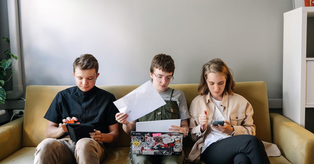 Tre unge personer som sitter i en sofa og jobber sammen